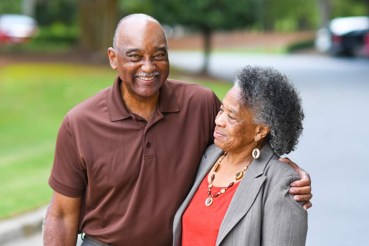 Senior couple living at Traditions at Bridgepointe Gardens enjoying a walk on the paved community walking paths
