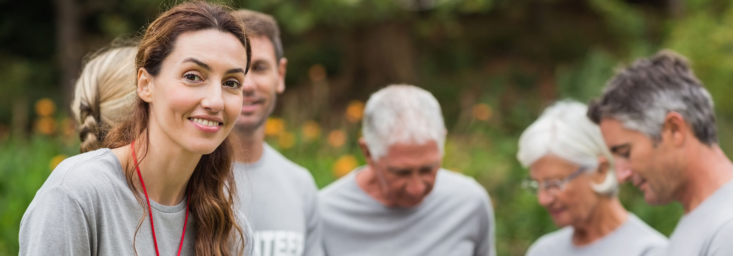 A photo of a female volunteer smiling with other volunteers working behind her
