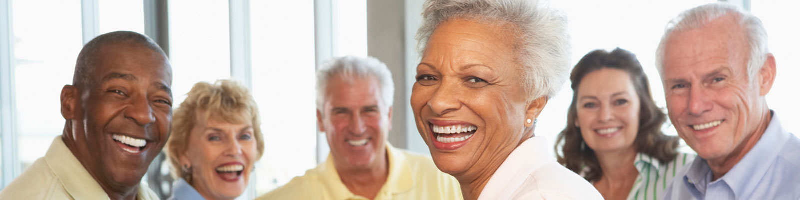 A group of senior men and women smiling as they sit together at a table
